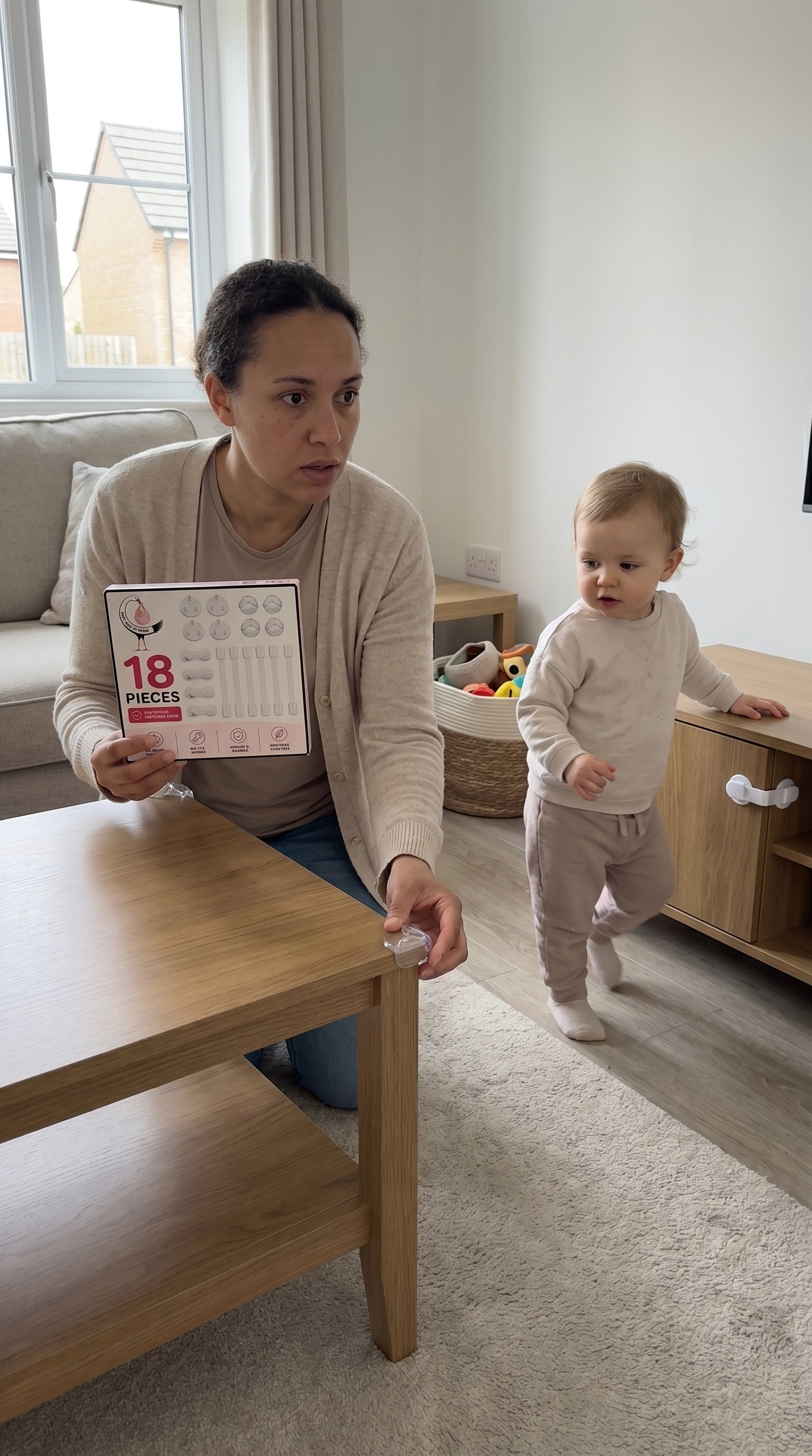 A parent beside a toddler and a protected coffee table